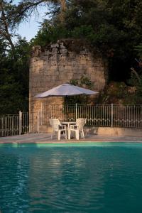 a table and chairs with an umbrella next to a pool at Enjoy Residencé Château de Monbrison, apartment for two guests in Saint-Michel