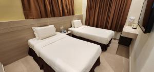 um quarto de hotel com duas camas e uma janela em Eighteen Guesthouse em Kuantan