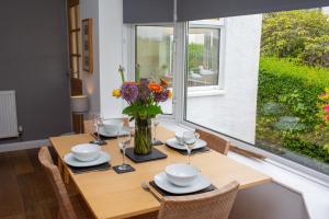 ein Esstisch mit einer Vase mit Blumen darauf in der Unterkunft Tryweryn Cottage Saundersfoot in Saundersfoot + 21 Fotos