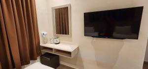 a bathroom with a toilet and a television on the wall at Eighteen Guesthouse in Kuantan