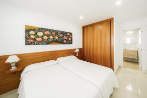 a bedroom with a white bed and a painting on the wall at Santa Margarita - Benisun in Benidorm +49 photos