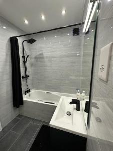 a bathroom with a sink and a bath tub at Remarkable 3-Bed Apartment in London in Hendon