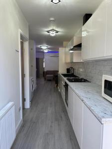 eine Küche mit weißen Schränken und einer Arbeitsplatte in der Unterkunft Impeccable 2-Bed Apartment in London in Hendon