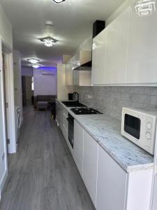 una cocina con armarios blancos y microondas en una encimera en Impeccable 2-Bed Apartment in London, en Hendon