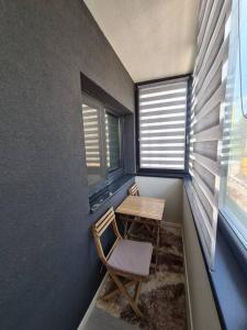 a room with a table and a chair and two windows at Confort Residence in Craiova