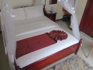 a bedroom with a white bed with a wooden frame at Acacia Country Inn in Mbarara