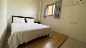 - une chambre avec un grand lit blanc et une fenêtre dans l'établissement 芹壁梅好石屋 Mayhao Stone House, à Beigan