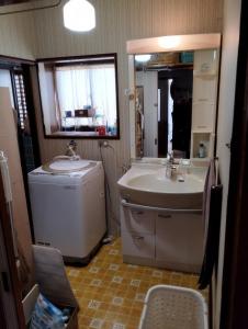a bathroom with a sink and a washing machine at ゲストハウスかもめ in Ishinomaki
