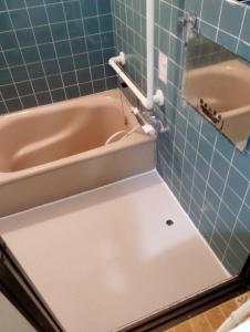 a bathroom with a bath tub and a sink at ゲストハウスかもめ in Ishinomaki