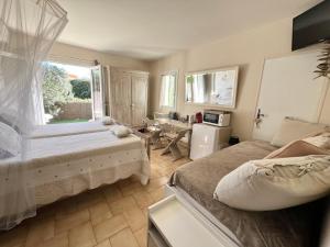 サント・マキシムにあるBastide du Levantのベッドルーム1室(ベッド2台、テーブル、窓付)