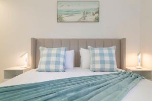 a bedroom with a bed with blue and white pillows at New Lux Apt opposite Buddina patrolled Beach in Buddina