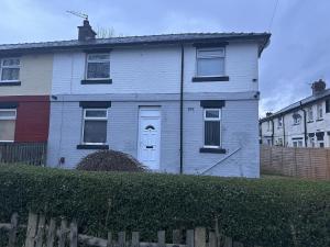 a white house with a fence in front of it at Beautiful 1-Bed House in Bradford in Bradford