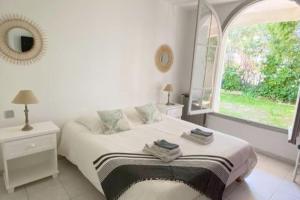 een witte slaapkamer met een bed en een raam bij Villa Reyosam ,la Maison du bonheur in Saint-Laurent-du-Var