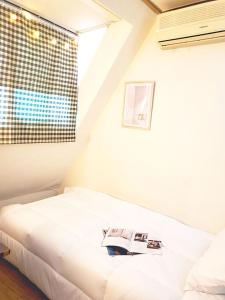 ein Schlafzimmer mit einem Bett mit einem Buch darauf in der Unterkunft NineRoD - Private bathroom & Shower in Seoul