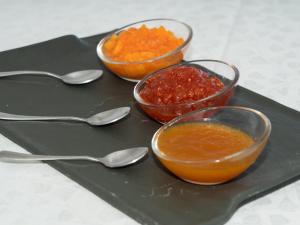 three bowls of sauce on a black tray with spoons at Balneario Pozo de la Salud in Sabinosa