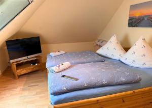 a bedroom with a bed with pillows and a television at Haus Seelotse in Otterndorf bei Cuxhaven in Otterndorf