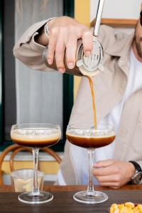 a person pouring a drink into two glasses at Casa Idalia Boutique Hotel in Comporta