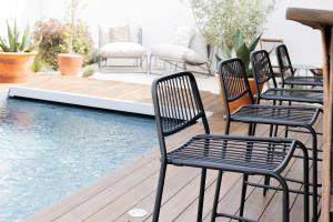four chairs sitting on a deck next to a swimming pool at Casa Idalia Boutique Hotel in Comporta