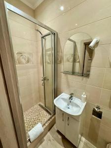 a bathroom with a shower and a sink and a mirror at Emerald Apartament in Chernivtsi