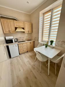 a kitchen with a white table and a white refrigerator at Emerald Apartament in Chernivtsi