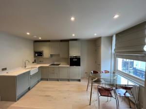 a kitchen with white cabinets and a glass table at Stunning Portobello Road flat in London