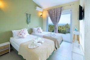 two beds in a room with a large window at Villa Agnanti in Vlachopoulátika +26 photos