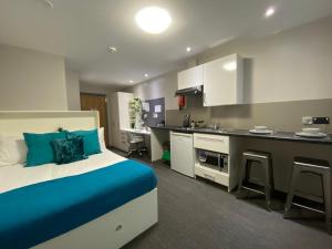 a bedroom with a blue bed and a kitchen at For Students Only Premium Studios and Private Ensuite Rooms at John Bell House in Belfast in Belfast