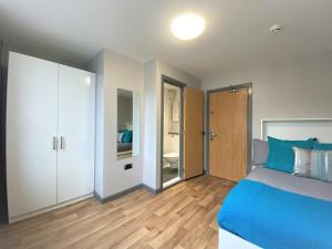 een slaapkamer met een blauw bed en een badkamer bij For Students Only Premium Studios and Private Ensuite Rooms at John Bell House in Belfast in Belfast