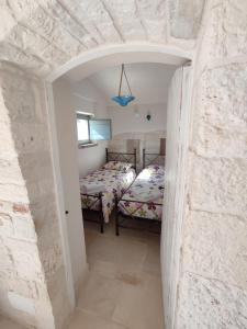 a bedroom with two beds and a stone wall at Le Dieci Porte in Alberobello
