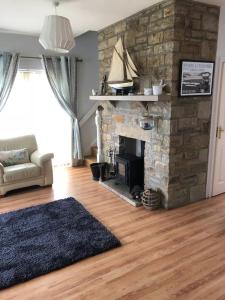 sala de estar con chimenea de piedra y sofá en Delightful Beach Retreat-, en Rossnowlagh