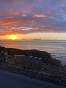 una puesta de sol sobre un cuerpo de agua con una valla en Delightful Beach Retreat-, en Rossnowlagh