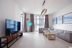 Brand New Luxury 2 Bedroom Apartment في أبوظبي: غرفة معيشة مع أريكة وتلفزيون كبير