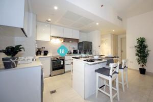 a kitchen with white cabinets and a table and chairs at Brand New Luxury 2 Bedroom Apartment in Abu Dhabi