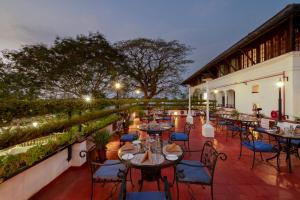ein Restaurant mit Tischen und Stühlen auf einer Terrasse in der Unterkunft Brunton Boatyard - CGH Earth in Kochi