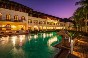 a large building with a swimming pool at night at Brunton Boatyard - CGH Earth in Cochin