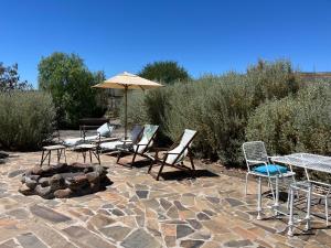a patio with chairs and a table and an umbrella at Kom Kyk Cottage in Merweville in Merweville