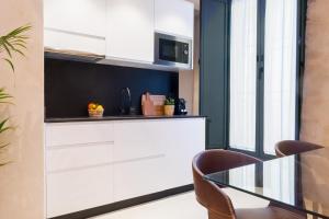 a kitchen with white cabinets and a glass table at Luxurious studio with Jacuzzi in Casa Pilatos in Seville