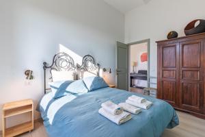 Un dormitorio con una cama azul con toallas. en Manufacto en Petroio