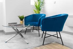 twee blauwe stoelen en een glazen tafel in een kamer bij Modern Apartment in Brierley Hill - Secure Parking - Wifi & Netflix - 11O in Brierley Hill