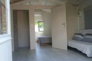 Un dormitorio blanco con una cama y una ventana. en Cosyhouse et piscine site web chalet du lagon wix, en Saint-Paul