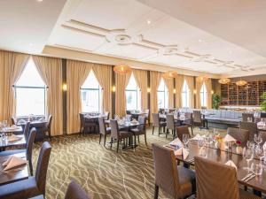 a dining room with tables and chairs and windows at Novotel Christchurch Cathedral Square in Christchurch