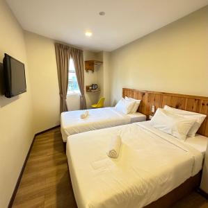 a hotel room with two beds and a tv at Swing & Pillows - Apple Hotel Shah Alam in Shah Alam