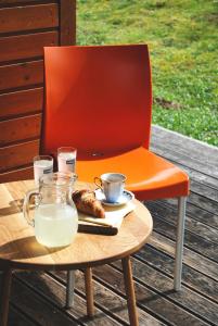 una sedia arancione seduta accanto a un tavolo con latte di Apartma Bazilika a Topolšica