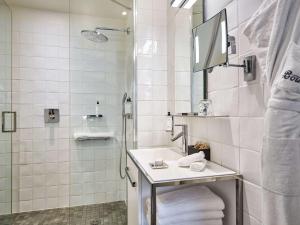 uma casa de banho branca com um lavatório e um chuveiro em Hôtel Paris Bastille Boutet - MGallery em Paris