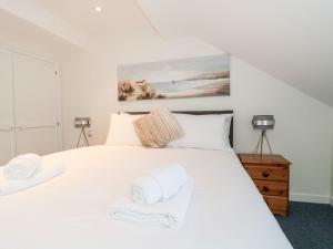um quarto com uma cama branca e toalhas em Mellstock em Weymouth