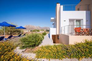 a house with chairs and umbrellas in the desert at Cretan View Apartments with sea view in Stavros