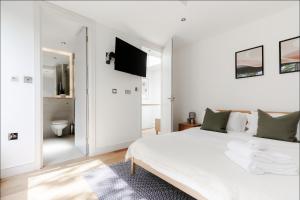 a white bedroom with a large bed and a bathroom at Spacious and sunlit 3-bedroom apartment near Paddington Station in London