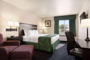 um quarto de hotel com uma cama e uma cadeira e uma janela em Travelodge by Wyndham McAlester em McAlester