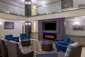 a waiting room with blue chairs and a fireplace at La Quinta by Wyndham Covington in Covington
