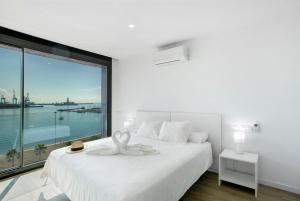 Un dormitorio con una cama blanca con una ventana grande. en Penthouse Sun beach best view, en Las Palmas de Gran Canaria